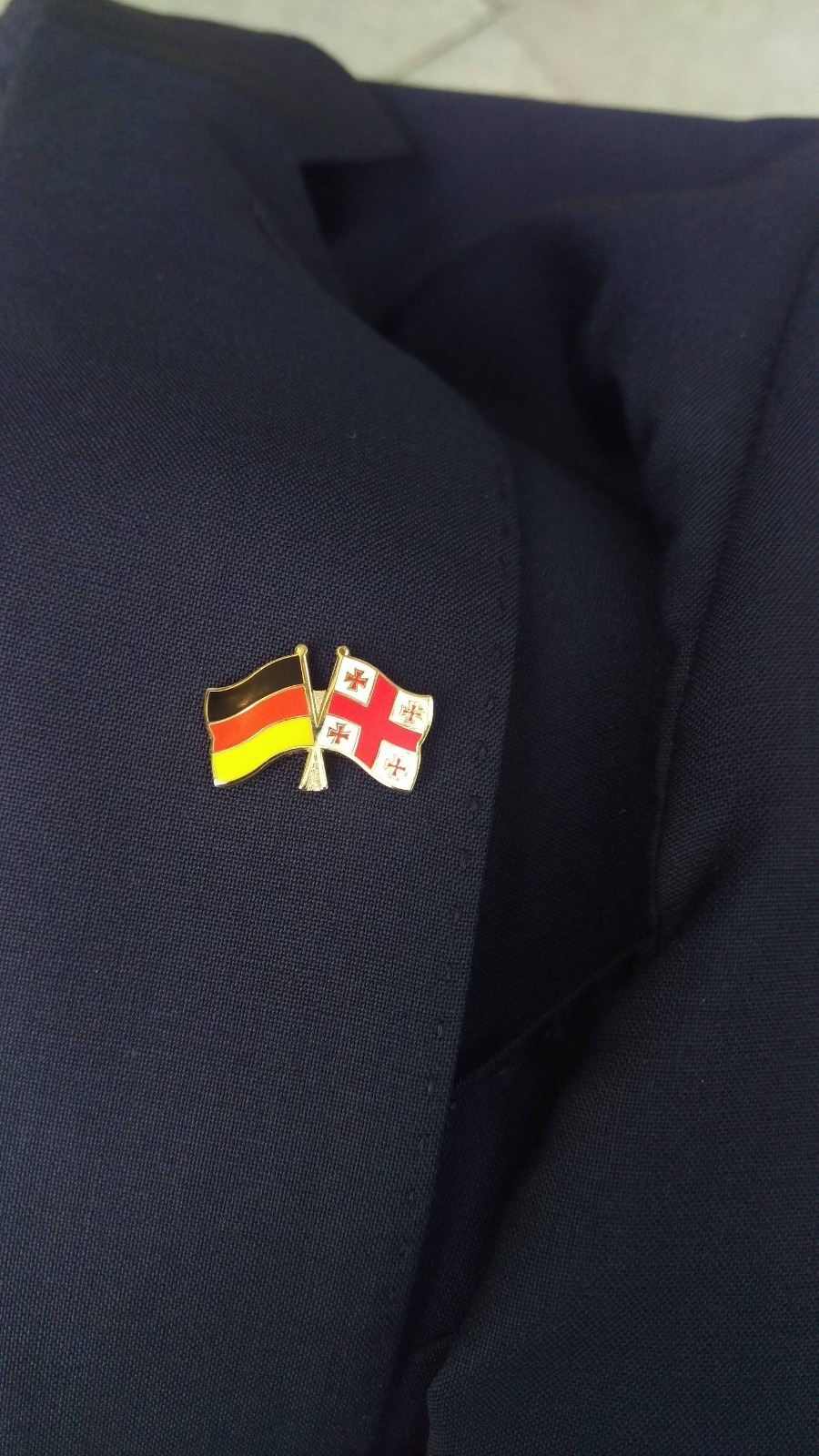 Bild eines Ansteckers auf dem Revers eines Anzugs mit den Flaggen von Georgien und Deutschland