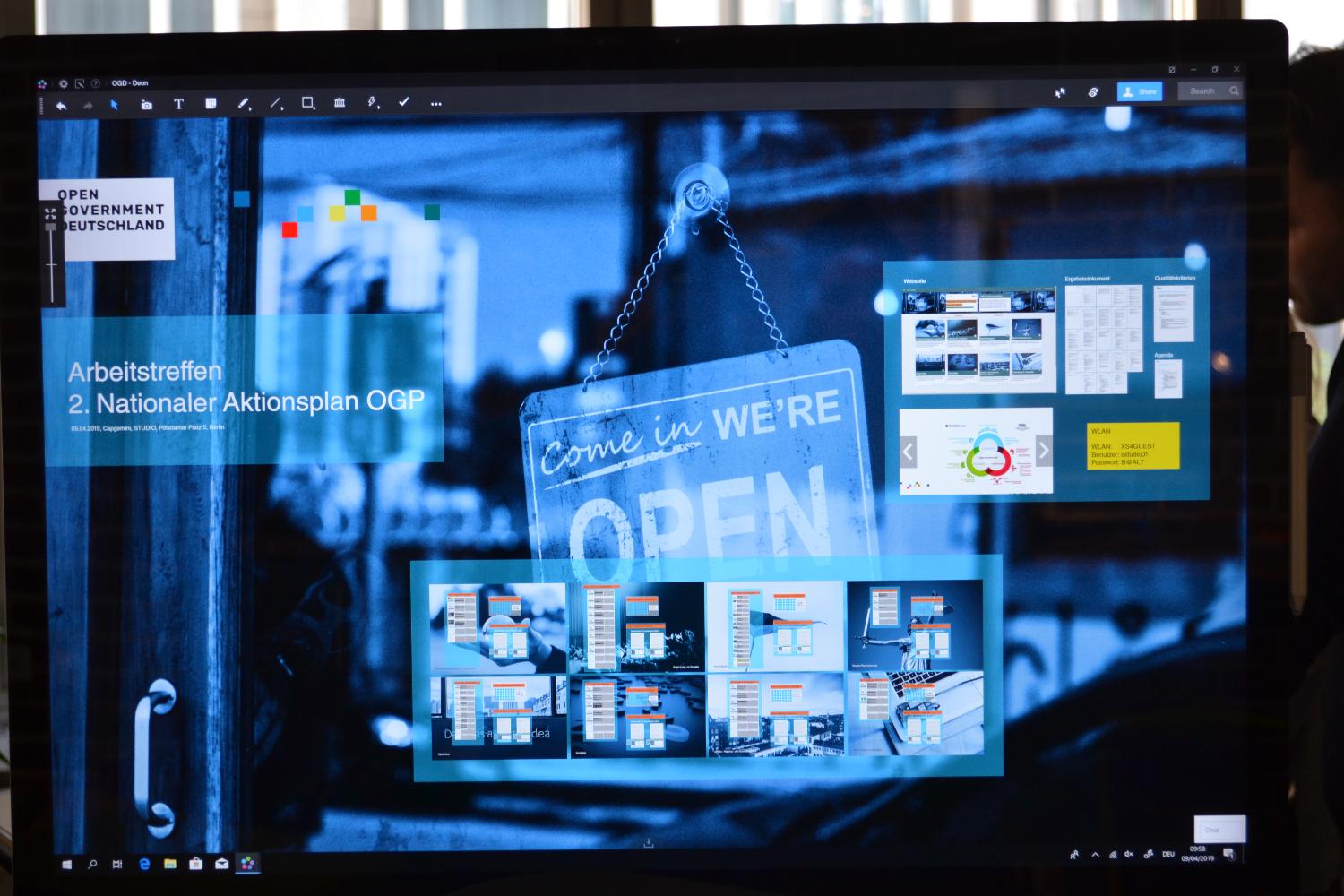 A screenshot shows the digital touch-screen interfaces of collaborative workspaces, in the background a "come in, we're open" sign is shown