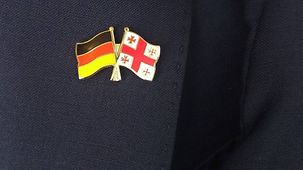 Bild eines Ansteckers auf dem Revers eines Anzugs mit den Flaggen von Georgien und Deutschland